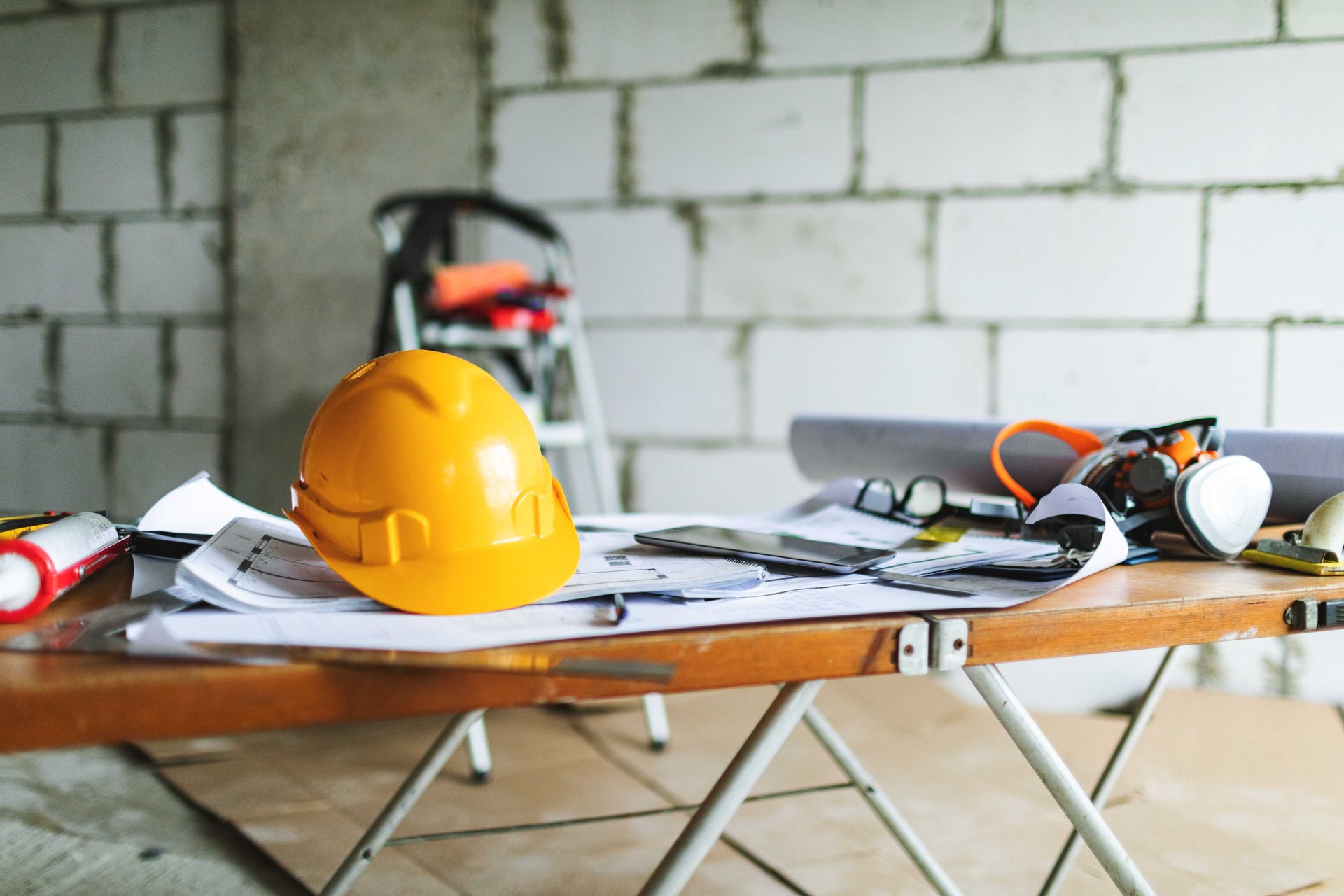 Architectural blueprints, hard hat and working tools on the table at construction site