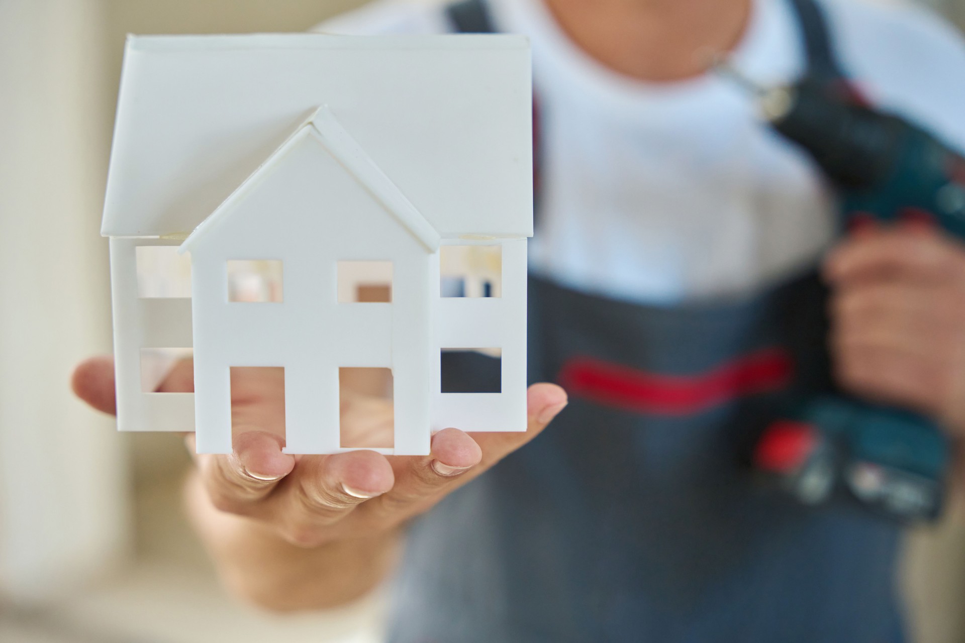 Foto ravvicinata del modello di casa nella mano del costruttore e nel trapano